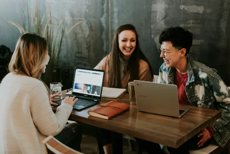 Diverse teammates smiling while collaborating at a laptop