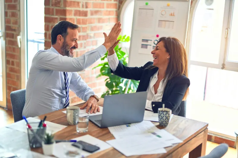 Colleagues collaborating around a laptop in an office